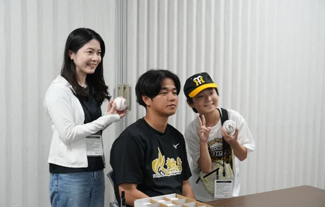 サインボールを手に笑顔の参加者と高橋投手