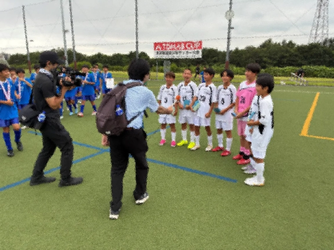 少年サッカーチームの子供たちが集まり、カメラマンが撮影している様子