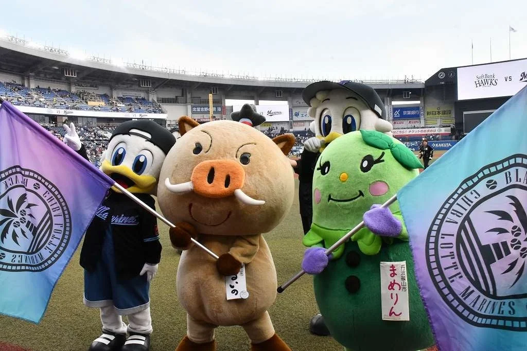 野球場のグラウンドで整列する千葉ロッテマリーンズのマスコットと地域キャラクター「まめりん」