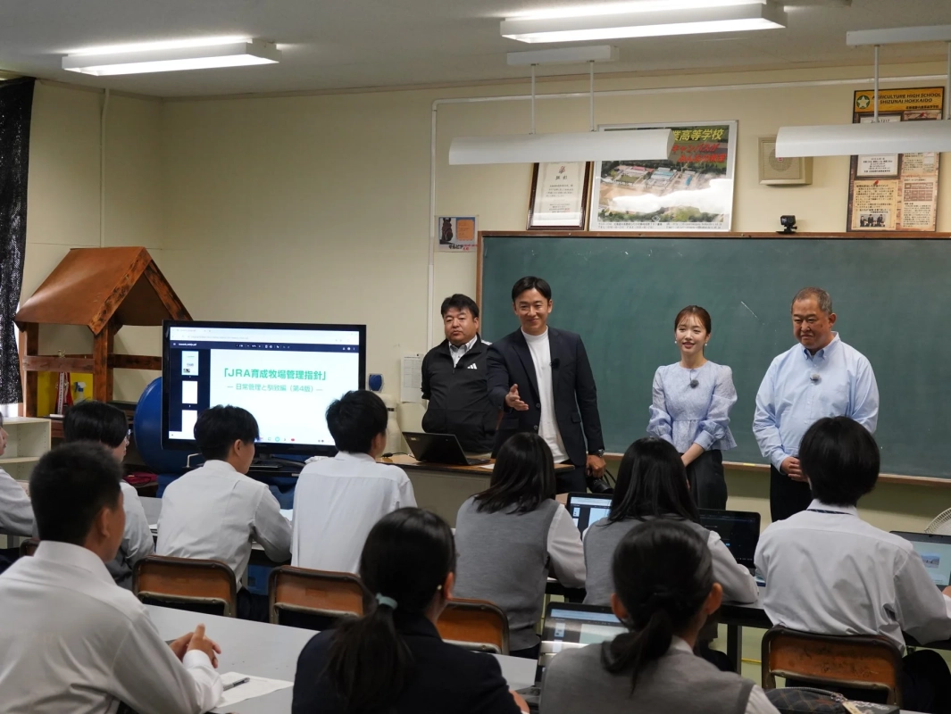 教室で、数人の大人が生徒たちにプレゼンテーションを行っている様子