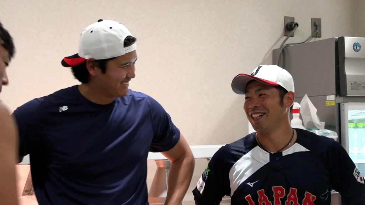 日本の野球選手2人が笑顔で談笑している様子。一人は「JAPAN」のユニフォームと「J」の帽子を着用しており、和やかな雰囲気が伝わってきます。