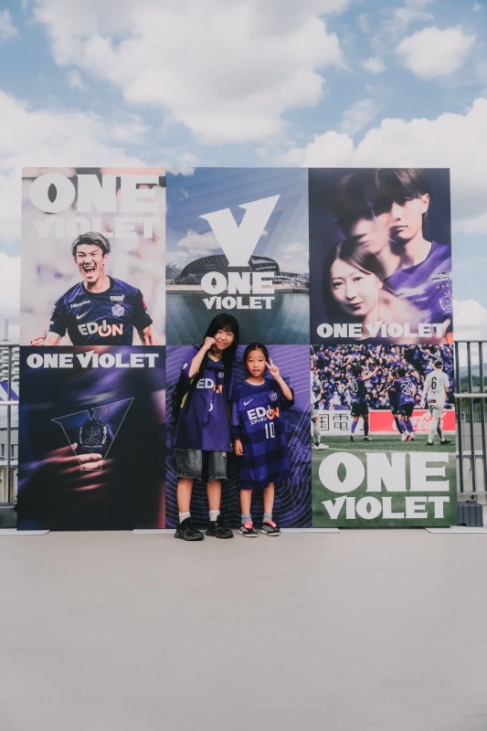 「ONE VIOLET」のロゴの前でポーズをとる子供たち