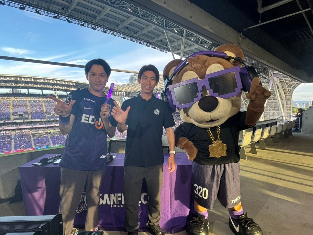 マスコットと男性がスタジアムでポーズ